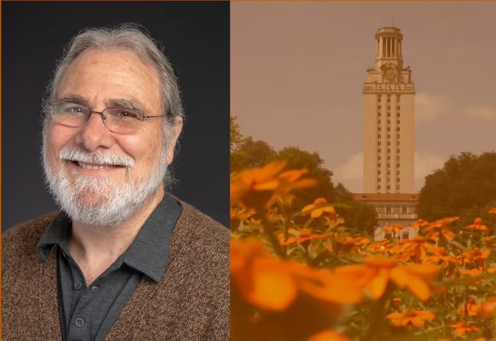 A bearded man in a sweater smiles. The UT Tower looms behind a bed of flowers.